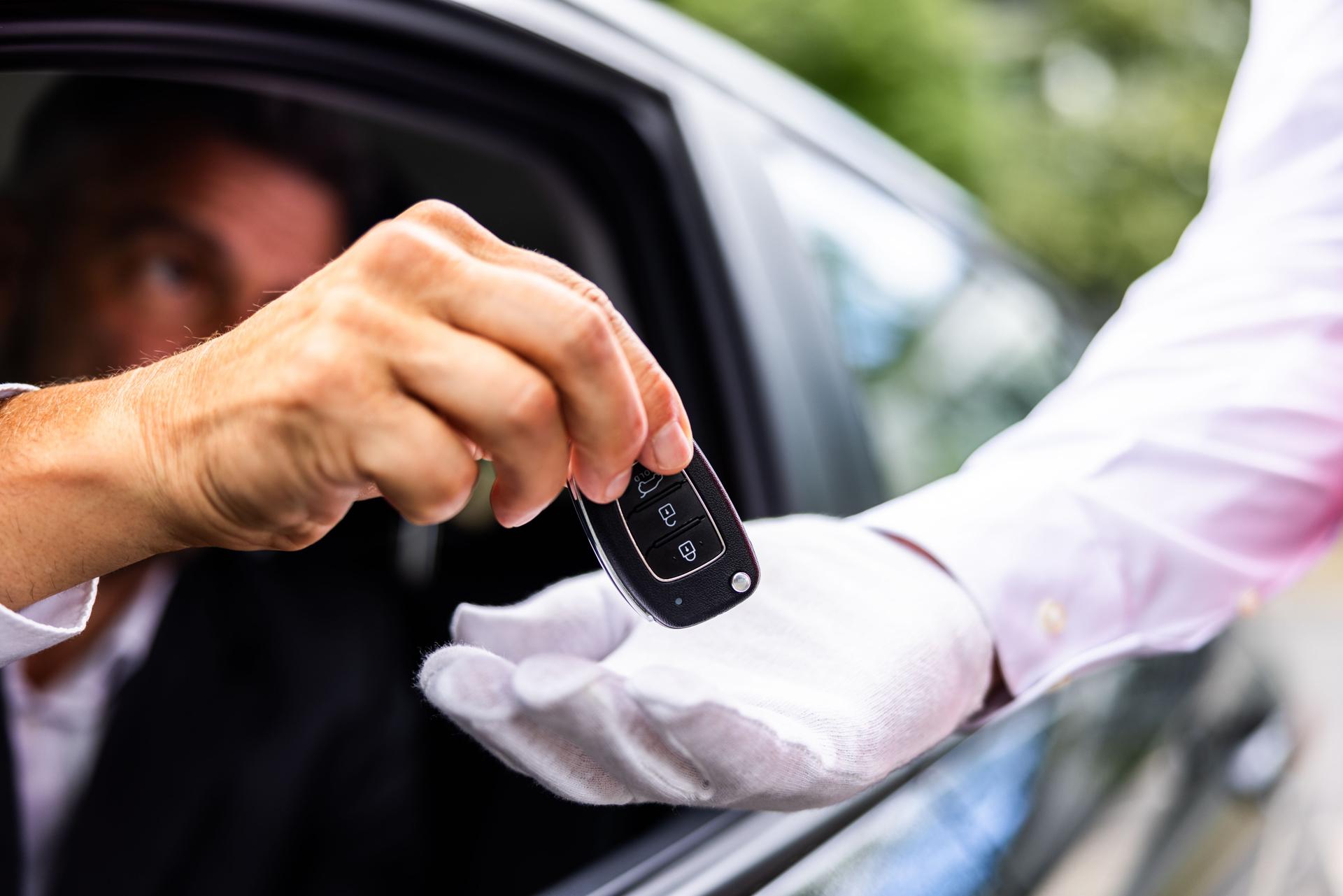 Luxury chauffeur service at a hotel: a businessperson's hand giving car key