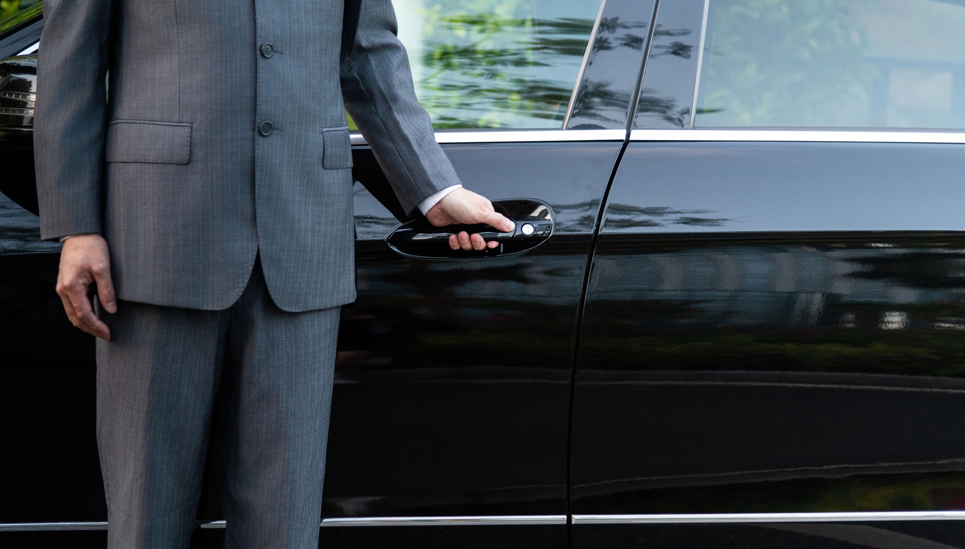 unrecognizable well dressed male chauffeur opening a car door